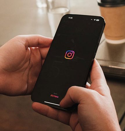 close up view of a person's hands holding a black smartphone opening the Instagram app