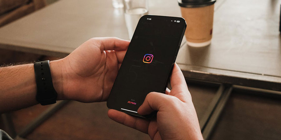 close up view of a person's hands holding a black smartphone opening the Instagram app